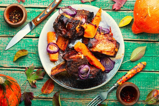 Côtes de boeuf BBQ sur table en bois. Viande de boeuf au four avec des tranches de citrouille