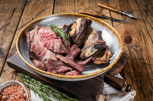 Côtes de bœuf de veau rôties en assiette au romarin. Fond en bois. Vue de dessus.