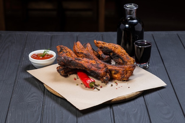 Côtes Frites Avec Du Poivre Et Une Bouteille De Vin Sur Une Surface En Bois Noir