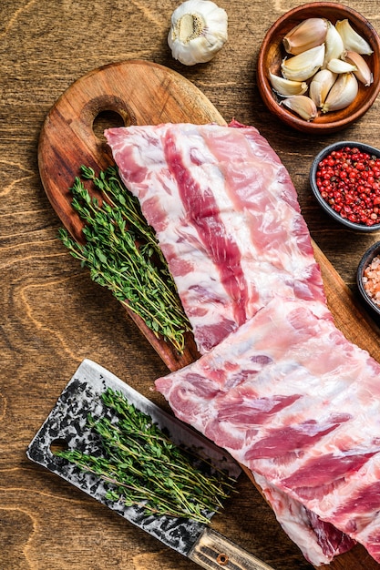 Côtes levées d'agneau cru frais avec des épices sur une planche à découper. Table en bois. Vue de dessus.