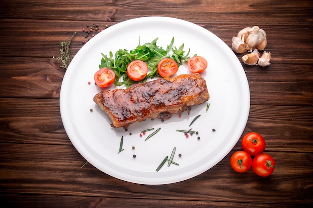 Côtes levées au barbecue délicieux assaisonnés avec des épices et des herbes fraîches sur fond en bois