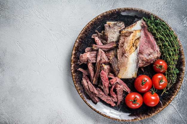 Côtes levées de boeuf fumé dans une assiette rustique avec des herbes Fond gris Vue de dessus Espace de copie