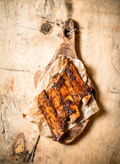 Côtes levées grillées sur l'ancienne planche sur fond de bois