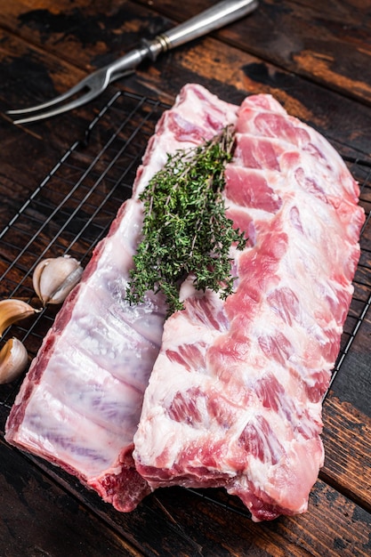 Côtes levées de porc crues sur une grille avec des herbes Fond en bois Vue de dessus