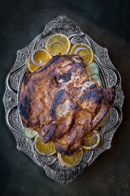 Côtes de mouton BBQ avec tranche d'oignon et de citron servies dans un plat isolé sur fond sombre vue de dessus