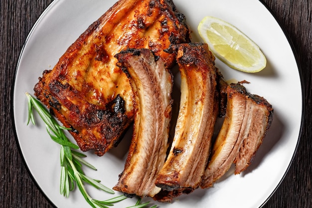 Côtes de porc au barbecue au citron et au romarin sur une assiette sur une table en bois sombre vue horizontale d'en haut