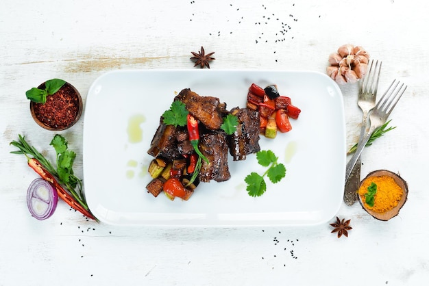 Côtes de porc au four avec des légumes. Dans l'assiette. Sur un fond en bois. Vue de dessus. Espace libre pour votre texte.