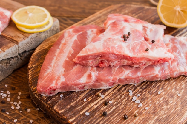 Côtes de porc aux épices non cuites sur une planche à découper en bois. Style rouillé.