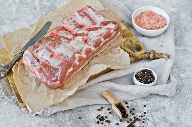 Côtes de porc cru sur une planche à découper en bois.