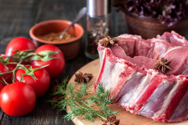 Côtes de porc crues aux légumes sur une table en bois