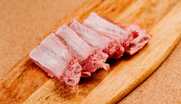 côtes de porc crues, coupées en morceaux sur une planche à découper. cuisiner de la viande à la maison. mains dans des gants jetables.