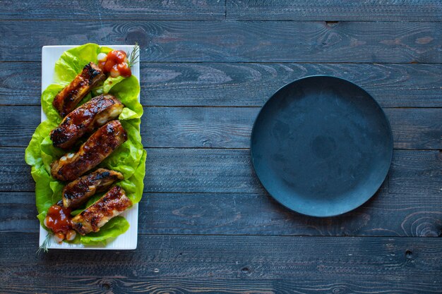 Côtes de porc grillées au barbecue avec des légumes sur une surface en bois; espace libre avant le texte.