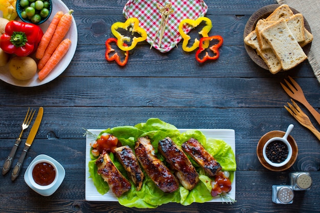 Côtes de porc grillées au barbecue avec des légumes sur une table en bois