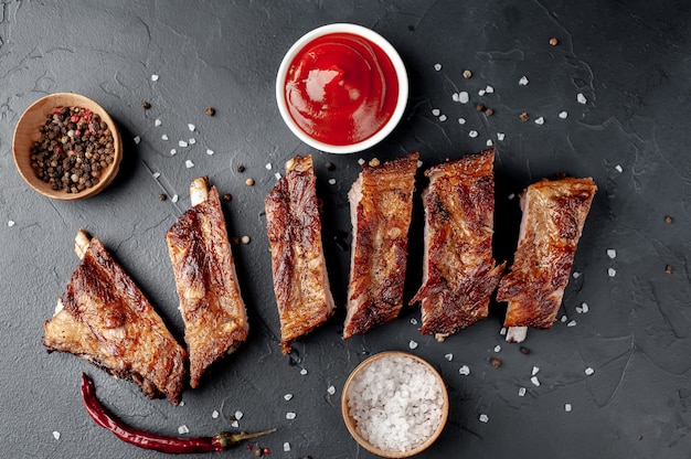 Côtes de porc grillées aux épices sur une planche à découper sur un fond de pierre