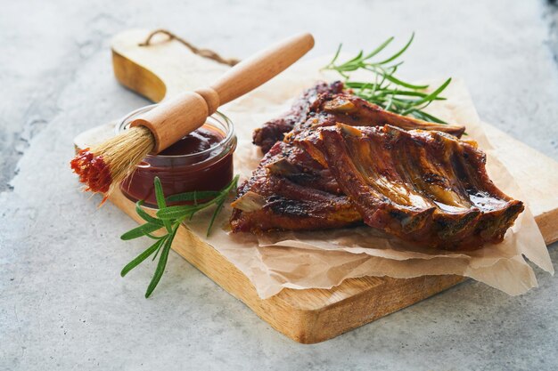 Côtes de porc grillées et fumées avec sauce barbecue sur une vieille planche à découper en bois vintage sur fond de table en bois Savoureuse collation à la bière Concept de cuisine américaine Vue de dessus