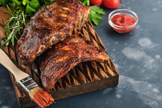 Côtes de porc grillées et fumées avec sauce barbecue sur une vieille planche à découper en bois vintage. Savoureuse collation à la bière. Image en gros plan.