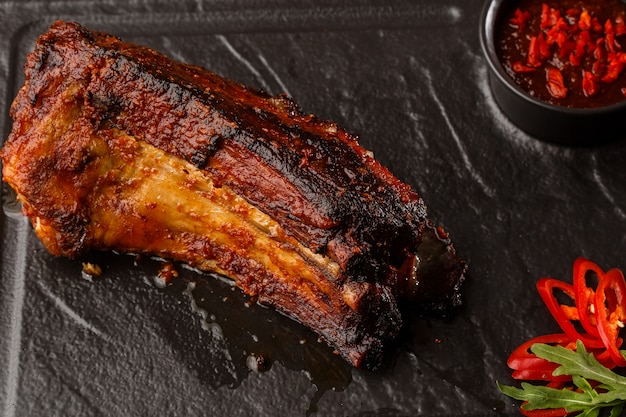 Côtes de porc grillées et grillées au piment fort et sauce piquante sur pierre noire