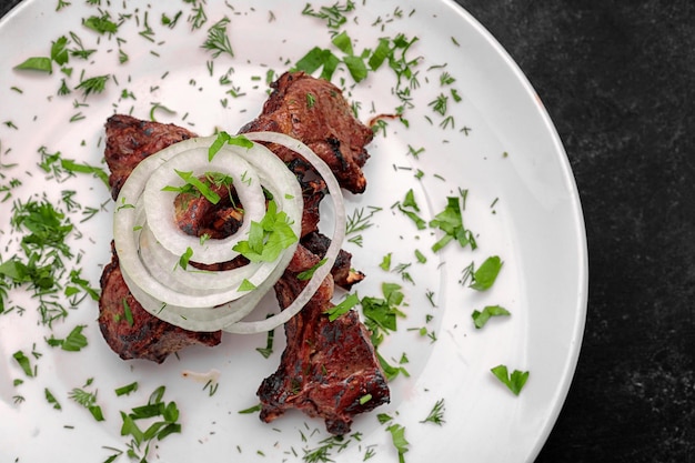 Côtes de porc grillées avec oignons et herbes sur fond sombre