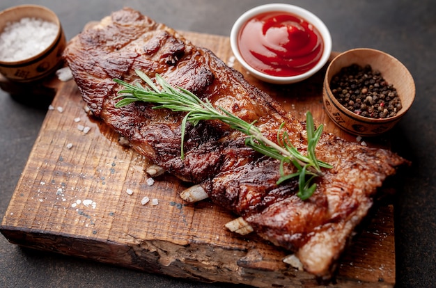 Côtes de porc grillées sur une planche à découper avec des épices sur un fond de pierre