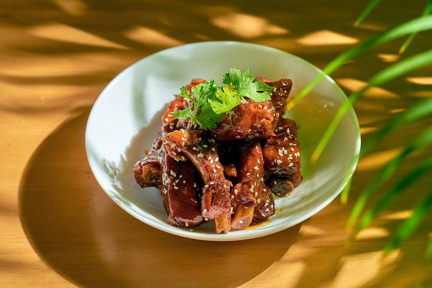 Côtes de porc à la sauce aigre-douce avec coriandre, graines de sésame et poivre du Sichuan dans un bol blanc. cuisine chinoise