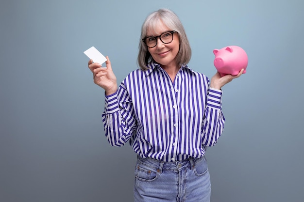 Cotisation de retraite femme d'âge moyen aux cheveux gris maîtrise les paiements sans numéraire détenant une carte de crédit