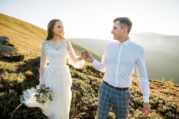 Le coucher du soleil illumine la colline de montagne où les couples de mariage marchent