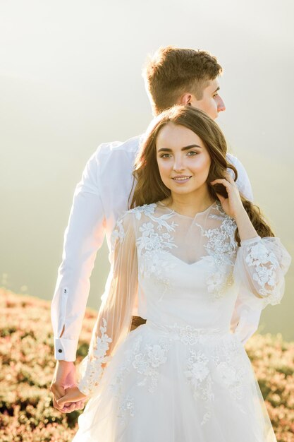 Le coucher du soleil illumine la colline de montagne où les couples de mariage marchent