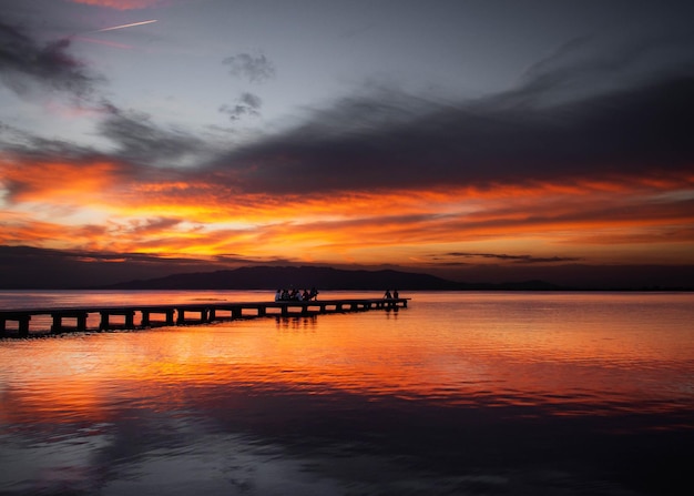 Photo coucher du soleil rouge avec des réflexions sur la mer avec un pilier