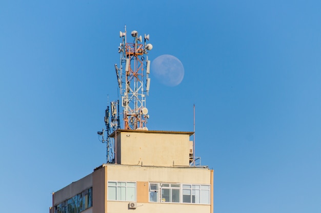 Coucher de lune derrière un bâtiment avec des antennes