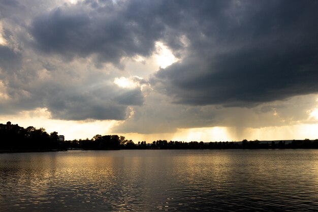 Coucher de soleil aérien ou lever de soleil sur un lac encadré de nuages épars de couleur variable.