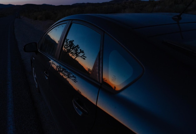 Photo le coucher de soleil de l'arbre joshua reflété dans la fenêtre de la voiture