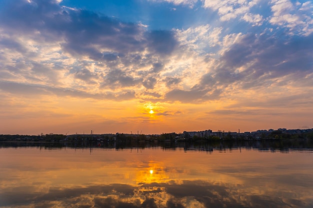 Coucher de soleil de beauté avec des nuages sur un lac calme dans la ville