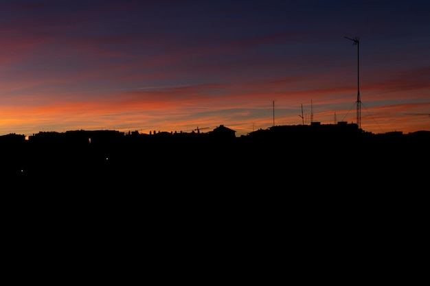 Coucher de soleil ciel coloré avec des silhouettes de maisons Ciel coloré pendant le coucher du soleil avec des silhouettes de maisons Beau ciel coloré avec des maisons en contre-jour