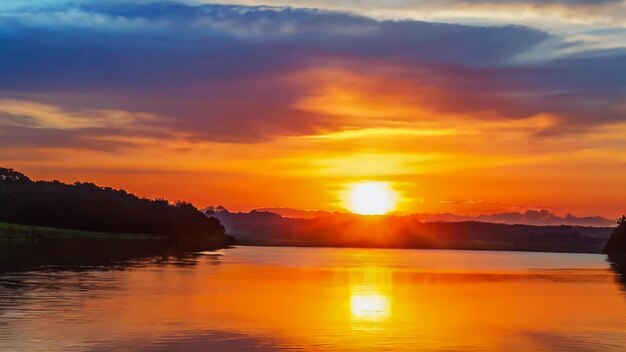 un coucher de soleil avec un ciel jaune et orange et un lac