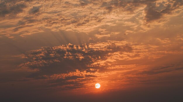 Photo un coucher de soleil avec un ciel nuageux et le soleil est visible.