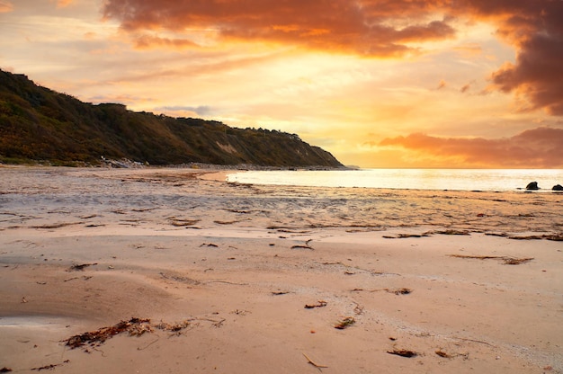 Coucher de soleil sur la côte danoise Vagues de la plage Colline avec des arbres en arrière-plan Paysage