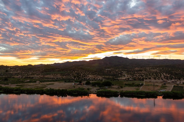 Coucher de soleil dans les montagnes et au parc éolien à côté de la rivière