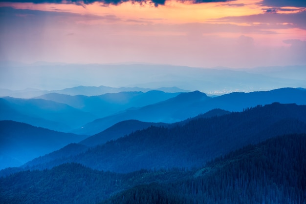 Coucher de soleil dans les montagnes avec des collines et un ciel coloré dramatique