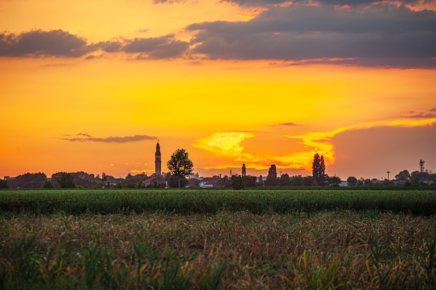 Coucher de soleil dans un paysage avec clocher, arbres et campagne