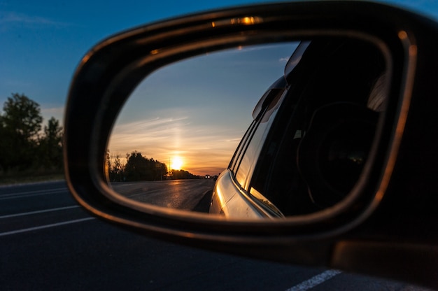 Coucher de soleil dans le rétroviseur d'une voiture