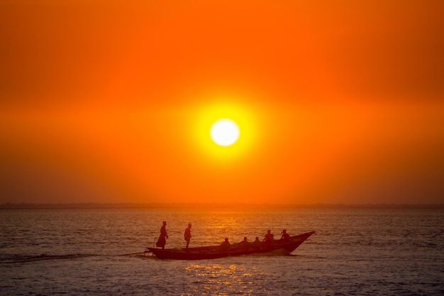 Coucher de soleil doré coloré sur la mer Les pêcheurs rentrent chez eux avec du poisson manuellement au coucher du soleil sur la plage de Char Samarj à Chandpur Bangladesh