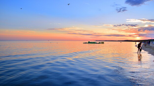 Un coucher de soleil d'été à l'horizon, une mer aux couleurs dorées et des nuages étonnants dans le ciel.