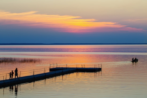 Coucher de soleil d'été sur le lac avec famille et bateau