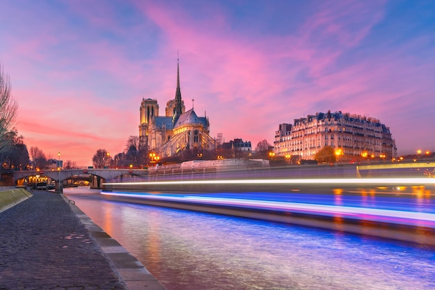 Coucher de soleil grandiose et pittoresque sur la cathédrale Notre-Dame de Paris et piste lumineuse depuis le bateau