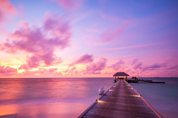 Coucher de soleil sur l'île des Maldives, complexe de luxe, jetée en bois beau ciel coloré et nuages et plage