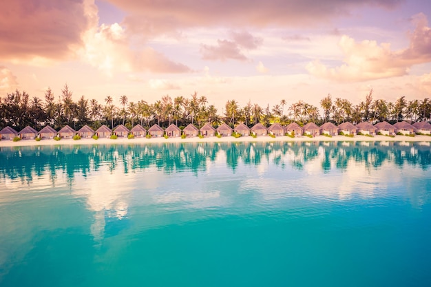 Coucher de soleil sur l'île des Maldives, hôtel de villégiature de villas de luxe sur l'eau et jetée en bois. Ciel et nuages colorés