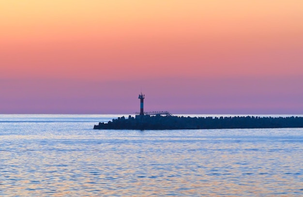 Coucher de soleil à la jetée du phare de Sotchi dans la zone d'eau de la station marine contre le rose