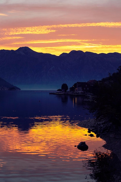 Un coucher de soleil sur un lac avec des montagnes en arrière-plan