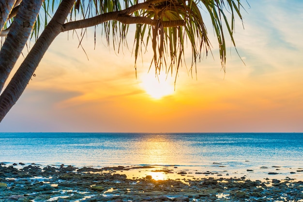 Coucher de soleil mer et plage avec cocotier et soleil couchant sur ciel dramatique