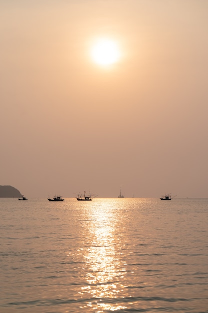 Coucher de soleil sur la mer avec sur la plage tropicale et ciel pastel orange.